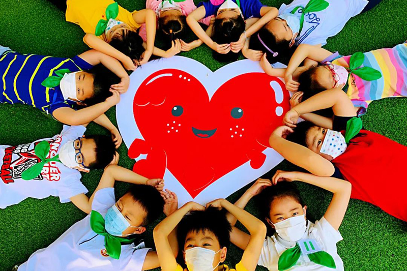 寶山區實驗小學學生們圍著愛心紙牌，躺成一個圈。（來源：上海教育微信公眾號）