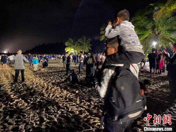 一位兒童坐著父親的肩上用望遠鏡觀看文昌航天發射場。凌楠 攝