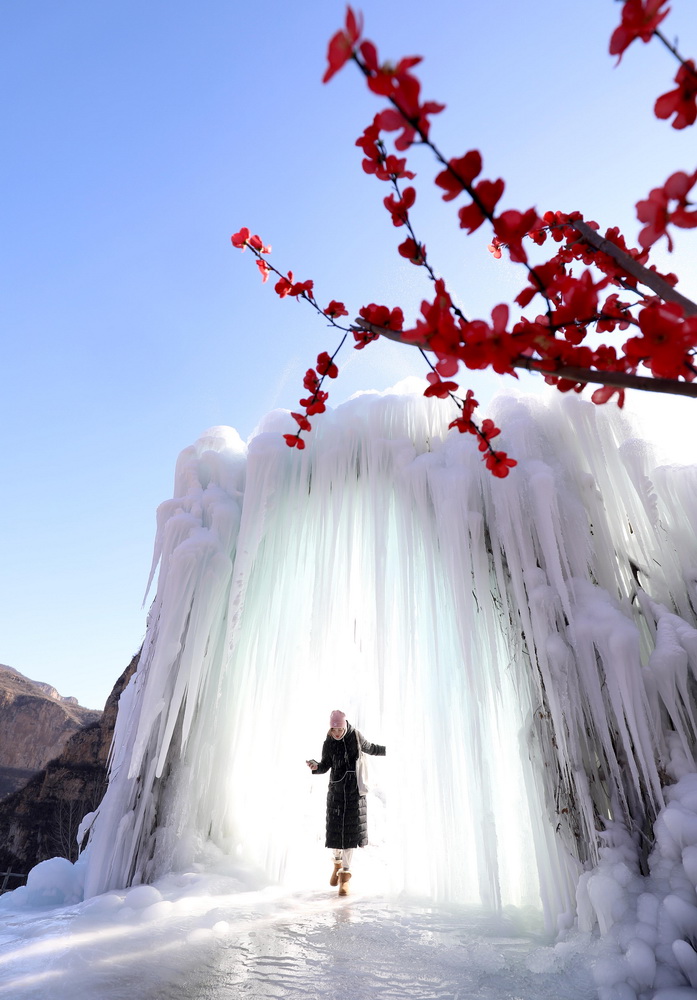 12月16日，在河北省平山縣沕沕水景區(qū)，游客在冰瀑中穿梭游玩。